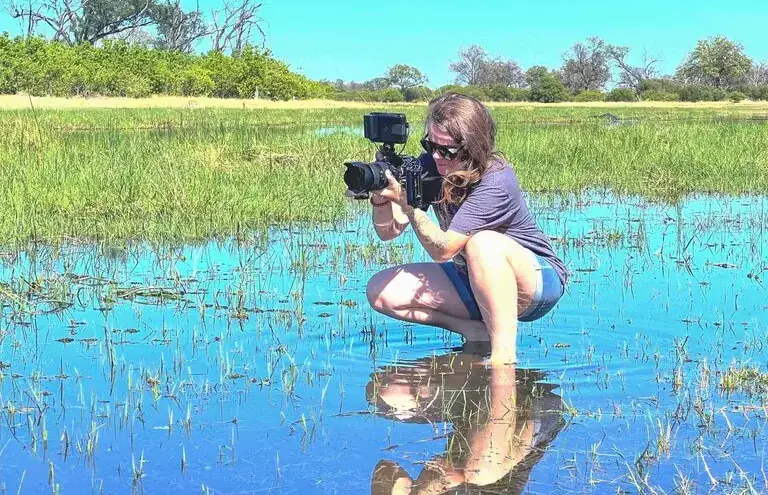 St. Louis video marketing footage: MEM Films videographer crouching in shallow marsh water to film wildlife on location