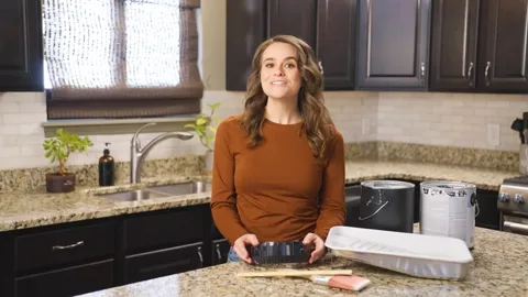 The DripLip product video by MEM Films: woman smiling behind a kitchen counter with paint rollers and trays