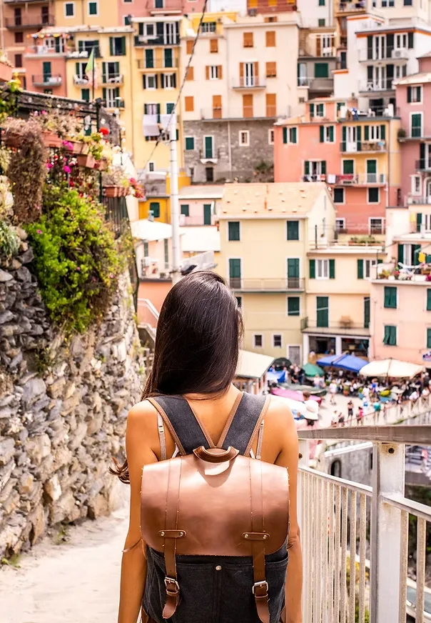 Specialized travel photography: traveler with a leather backpack overlooking colorful cliffside houses on the Italian coast