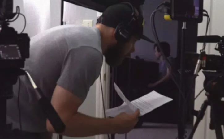 Testimonial video production for St. Peters, MO companies: Mark Mattei of MEM Films in headphones reading a script beside a cinema camera
