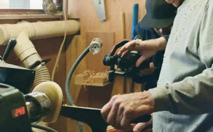 Home service video production in St. Louis: woodturner shaping a piece on a lathe while filmed with a handheld gimbal camera