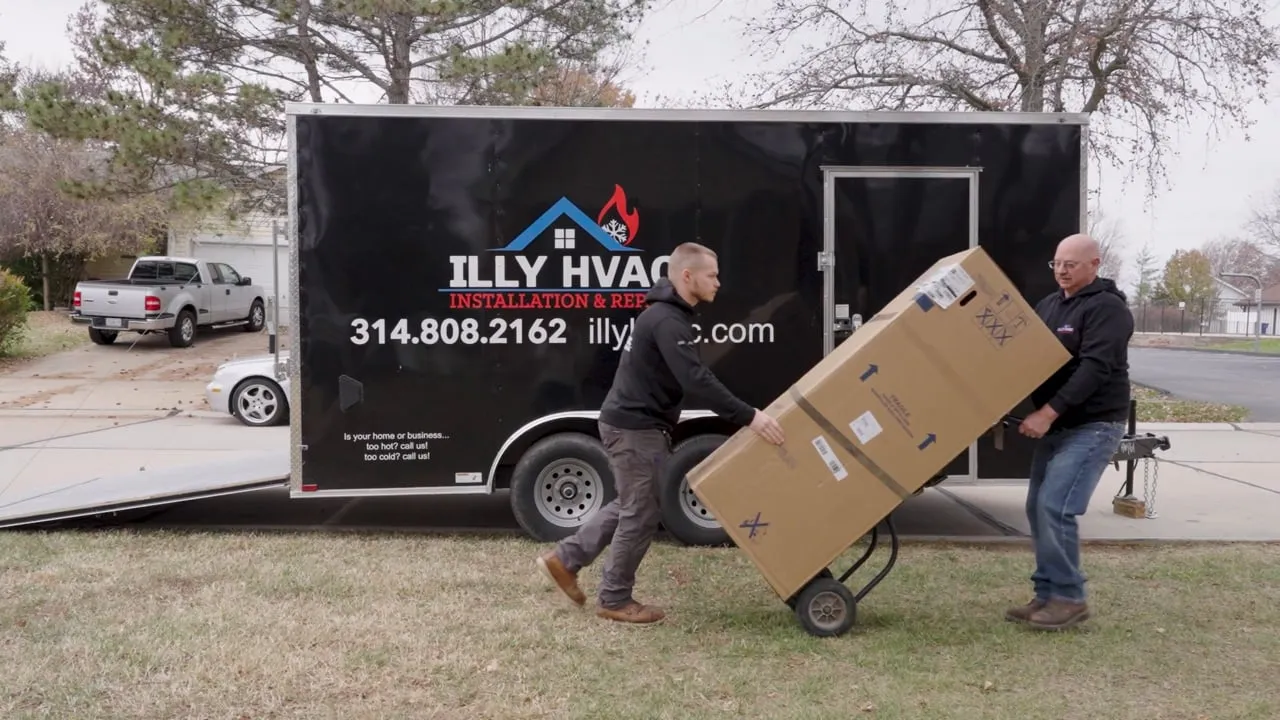 Illy HVAC video: two technicians unloading a boxed furnace from a branded trailer on a suburban street
